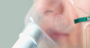 A person is attached to an oxygen mask.