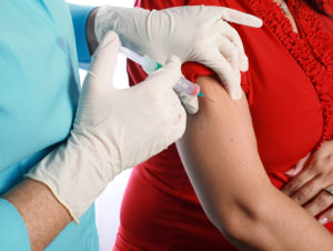 A medical professional gives a woman a Tdap vaccine.