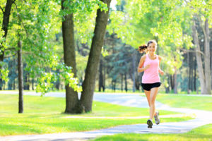A woman runs on a trail outside.