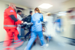 A group of medical professionals rush a patient into a hospital.