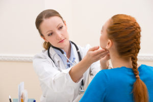 A medical professional touches a woman's jaw.