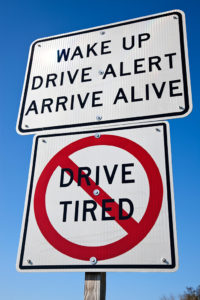 A sign reads, 'Wake Up. Drive Alert. Arrive Alive.' 