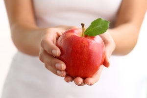 A person holds a red apple.