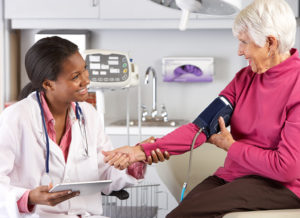 An elderly adult has her blood pressure measured by a medical professional.