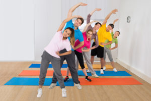 A group of people stretch together on yoga mats.