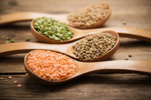 Lentils are shown in wooden spoons. 