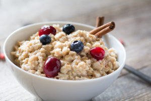 A bowl of oatmeal is shown with cherries, blueberries and cinnamon on top.