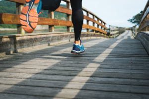 A person runs on a bridge wearing compression tights and tennis shoes.
