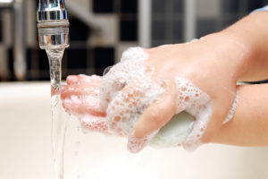 A person washes their hands under water with soap.