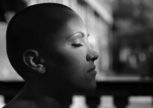 A woman with no hair closes her eyes. 