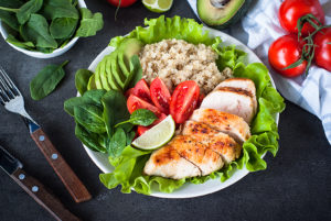 A white plate with veggies, quinoa and grilled chicken is shown.