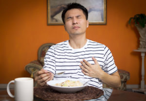 A man experiences heartburn as he eats food.