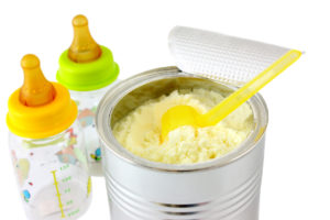 A can on infant formula is shown next to two baby bottles.