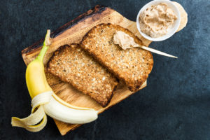 A banana and two pieces of toast with peanut butter are shown.