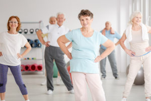 A group of elderly adults stretch together at a workout class.