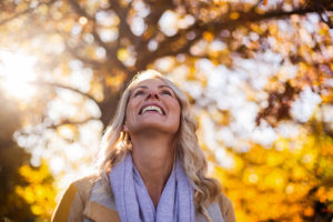 A woman stares up into the sky and smiles big.