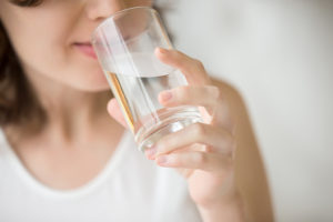 A woman drinks a glass of water.