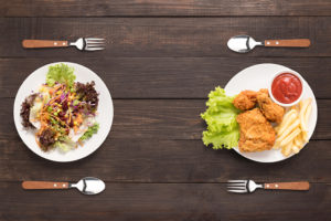 Two plates of food are shown. One plate has a salad, the other plate has fried food.