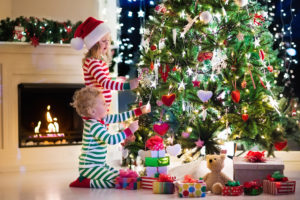 Two young kids decorate a Christmas tree together.