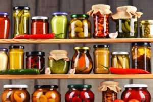 A pantry is shown with many glass jars full of vegetables, spices, fruit, and other healthy ingredients.