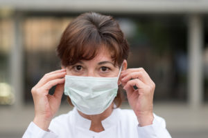 A woman places a medical mask on her face.