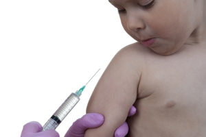 A baby appears to be given a vaccine. The baby is looking at the needle.