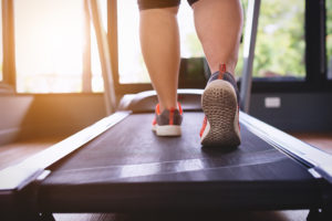 A person walks on a treadmill with tennis shoes.