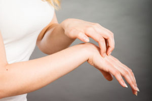 A woman scratches her wrist.