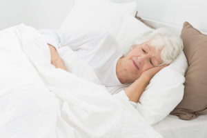 An elderly woman appears to be sleeping in a bed.