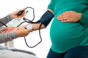 A pregnant woman has her blood pressure measured by a doctor.
