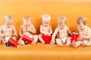 Five babies sit down with buckets of popcorn.