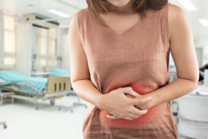 A woman holds her stomach. She appears uncomfortable.