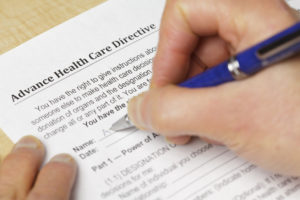 A person fills out a 'Advance Health Care Directive' form.