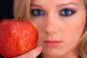 A woman holds a red apple.