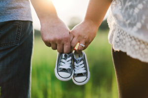 A man and a woman hold baby shoes together.