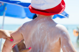 A little boy's back is covered with sunscreen.