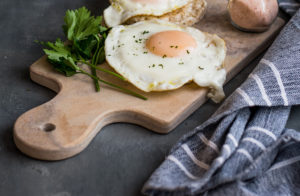 A hard boiled egg is on a cutting board next to a kitchen towel.