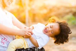 A woman plays with her child outside. They both appear happy.