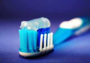 A blue toothbrush with toothpaste is in focus.