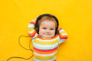 A young kid listens to music through headphones.
