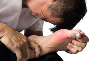 A person holds their foot and appears in pain.