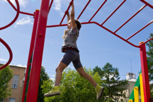 A young girl plays on the monkey bars.