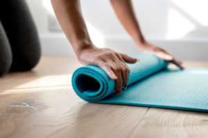 A person unravels their yoga mat.