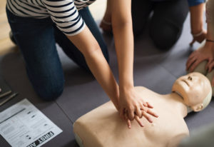 A person performs CPR on a mannequin.