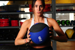 A woman holds a '6KB' medicine ball.