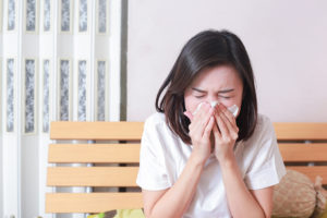 A woman sneezes or blows her nose into a tissue.