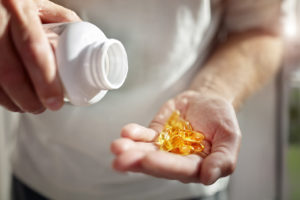 A person pours Vitamin D supplements in their hand.