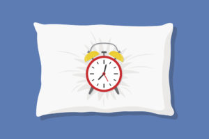 An alarm clock lies in a pillow.