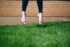A person jumps in the air outside. Their feet are in focus, they are about a foot off of the ground.
