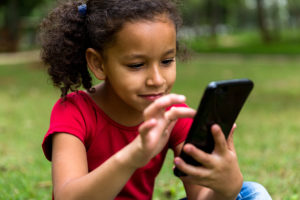 A young girl touches a screen of a cellphone.